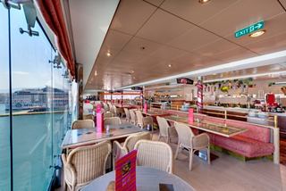 A vibrant dining area with panoramic views, featuring tables and a welcoming atmosphere for guests | MSC Cruises