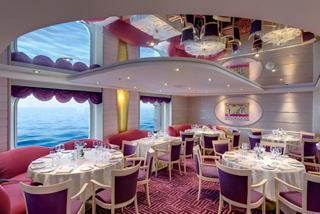 Elegant dining area with tables and chairs, offering stunning sea views through large windows | MSC Cruises
