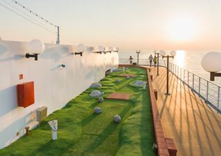 A vibrant mini golf area with lush grass on the deck of MSC Opera at sunset, overlooking the serene sea | MSC Cruises