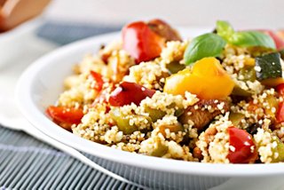 A vibrant bowl filled with couscous and assorted fresh vegetables garnished with basil leaves | MSC Cruises