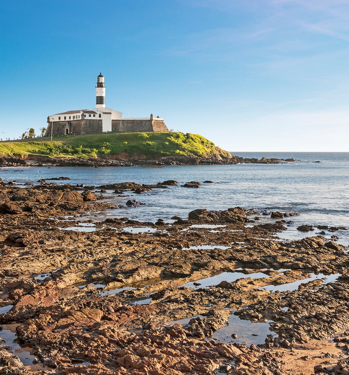 A scenic view of a lighthouse on a rocky coastline in Salvador de Bahia, Brazil, surrounded by the sea | MSC Cruises