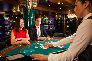 A couple enjoys a game of blackjack at the Palm Beach Casino with attentive staff on MSC Orchestra | MSC Cruises