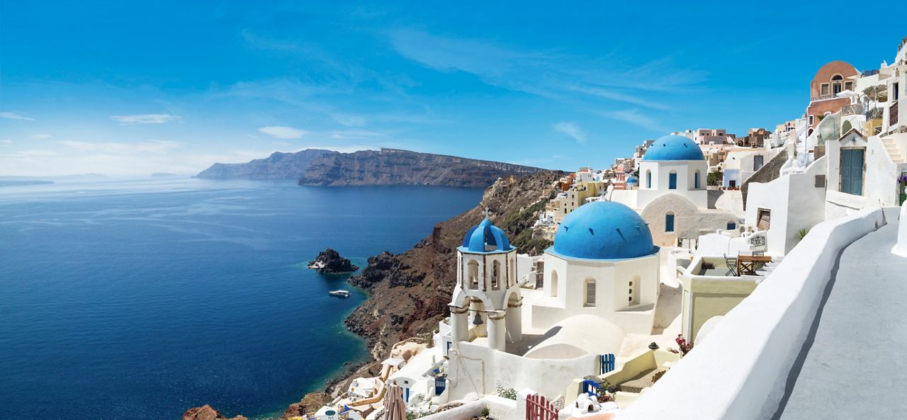 Une vue panoramique de la côte époustouflante de Santorin, avec des bâtiments blancs et des dômes bleus face à la mer | MSC Cruises