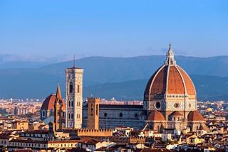 A panoramic view of Florence featuring the famous cathedral dome and bell tower against a clear blue sky | MSC Cruises