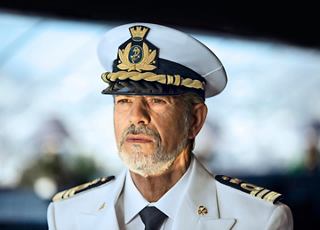 A naval officer stands proudly in the wheelhouse, embodying leadership and dedication aboard MSC Splendida | MSC Cruises
