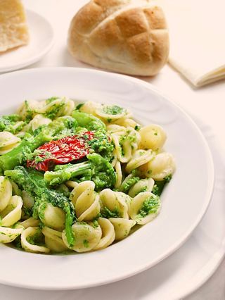 A delicious plate of orecchiette pasta with greens and a slice of bread on the side | MSC Cruises