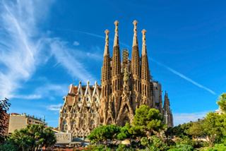 La Sagrada Familia, emblématique, se dresse majestueusement sous un ciel bleu éclatant à Barcelone, entourée de verdure luxuriante | MSC Croisières