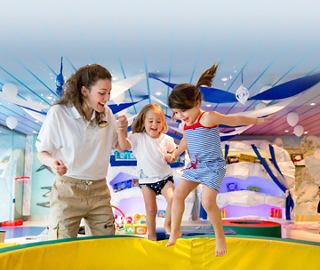 A parent and two children enjoy playful moments together in a vibrant onboard entertainment area | MSC Cruises