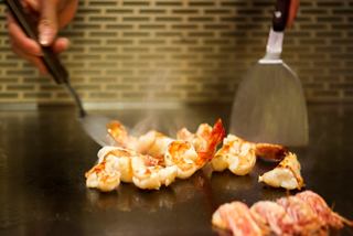 A chef skillfully prepares shrimp at a teppanyaki restaurant | MSC Cruises