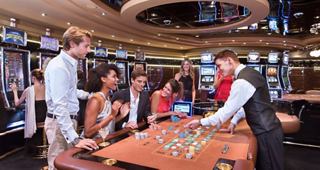 A group of people enjoys gaming at the casino with a dealer | MSC Cruises