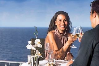 A couple enjoys a toast with wine at a table by the sea, creating a memorable moment on board MSC Preziosa | MSC Cruises