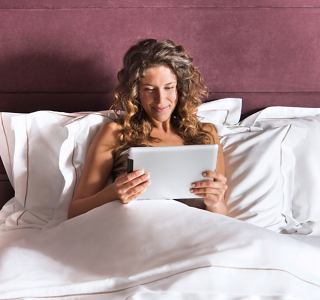 A woman using a tablet in bed, enjoying a relaxing moment | MSC Cruises
