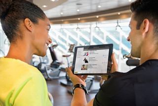 Zwei Personen nutzen ein Tablet im Fitnessstudio, teilen Fitness-Einblicke und fördern ein Wellness-Erlebnis | MSC Cruises
