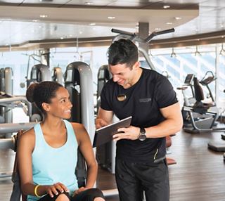 A fitness instructor guides a woman in a gym setting, promoting a healthy lifestyle and personalised training | MSC Cruises