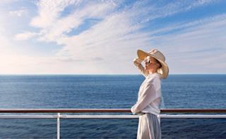 A woman in a hat enjoys the sea breeze from the deck of MSC Preziosa, embracing life on board | MSC Cruises