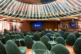 The interior of L'Insolito Lounge featuring green seating, a large monitor, and a domed ceiling | MSC Cruises