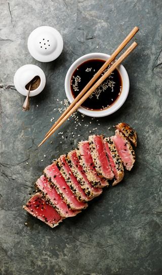 Tuna sashimi garnished with sesame seeds, served with soy sauce and chopsticks | MSC Cruises