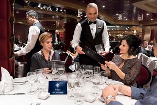Guests enjoy a dining experience as a waiter serves wine in an elegant restaurant aboard MSC Fantasia | MSC Cruises