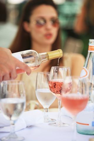 Eine Frau genießt ein erfrischendes Getränk an einem wunderschön gedeckten Tisch in einer lebhaften Restaurantatmosphäre | MSC Cruises