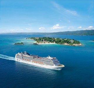Un navire de croisière s'approche d'une île pittoresque sous un ciel bleu clair | MSC Cruises
