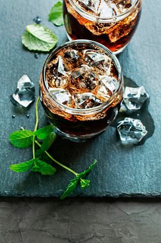 Two refreshing cocktails with ice and mint leaves are served in jars on a dark surface | MSC Cruises