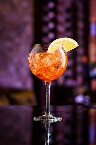 A vibrant cocktail garnished with a slice of lemon, served in a glass over ice | MSC Cruises