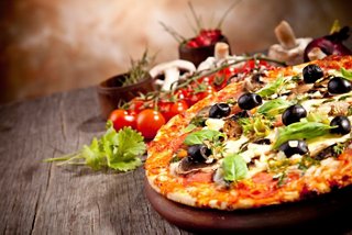 A delicious pizza topped with fresh ingredients including olives, mushrooms, and herbs | MSC Cruises