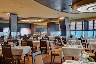 A spacious dining area featuring elegant tables and large windows offering sea views | MSC Cruises