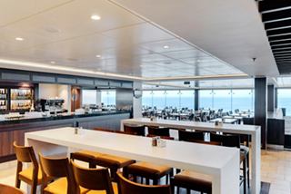 A spacious dining area with large windows offering sea views, featuring tables and a welcoming atmosphere | MSC Cruises