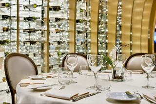 Elegant dining table set for a meal, surrounded by a beautiful wine display in L'Olivo D'Oro restaurant | MSC Cruises