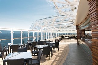 A spacious outdoor dining area with elegant seating and stunning ocean views aboard MSC Yacht Club | MSC Cruises