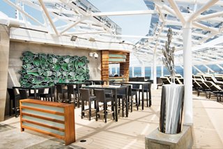 A vibrant outdoor bar area with seating and a stunning view, perfect for relaxation on the MSC Yacht Club Sundeck | MSC Cruises