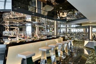 Un área de bar elegante con un diseño contemporáneo, que ofrece un ambiente cálido para que los huéspedes se relajen y disfruten de bebidas | MSC Cruceros