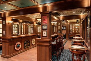 A warm and inviting interior of the Brass Anchor Pub on MSC Meraviglia, featuring wooden furnishings and cosy seating | MSC Cruises
