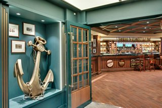 A welcoming view of the Brass Anchor Pub on MSC Meraviglia, featuring a decorative anchor and bar counter | MSC Cruises