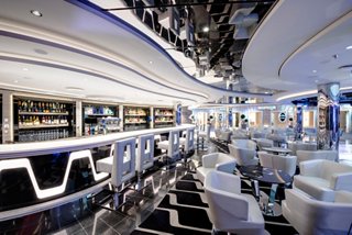 A spacious and elegant lounge area with stylish seating and a welcoming bar for relaxing moments at sea | MSC Cruises
