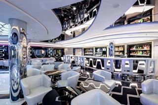 A stylish and inviting lounge area featuring elegant seating and a bar counter | MSC Cruises