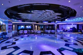 A stylish lounge featuring a vibrant dance floor, stage, and inviting seating for entertainment and relaxation | MSC Cruises