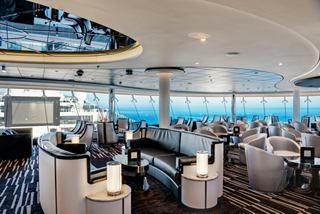 A stylish Sky Lounge with panoramic sea views, featuring elegant seating and tables for guests to enjoy | MSC Cruises