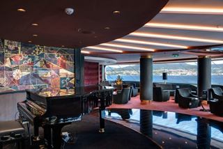 Elegant lounge area of the Top Sail Lounge, showcasing panoramic views of the sea and coastline | MSC Cruises