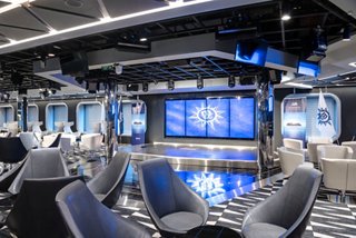 A spacious TV studio and bar area with comfortable seating and large screens for entertainment | MSC Cruises