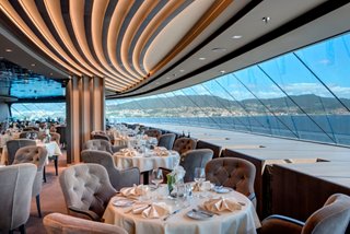 A beautifully arranged dining area in the MSC Yacht Club with stunning sea views through expansive windows | MSC Cruises