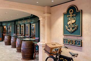 A welcoming interior of the Brass Anchor Pub on MSC Meraviglia, featuring barrels and a warm, inviting atmosphere | MSC Cruises