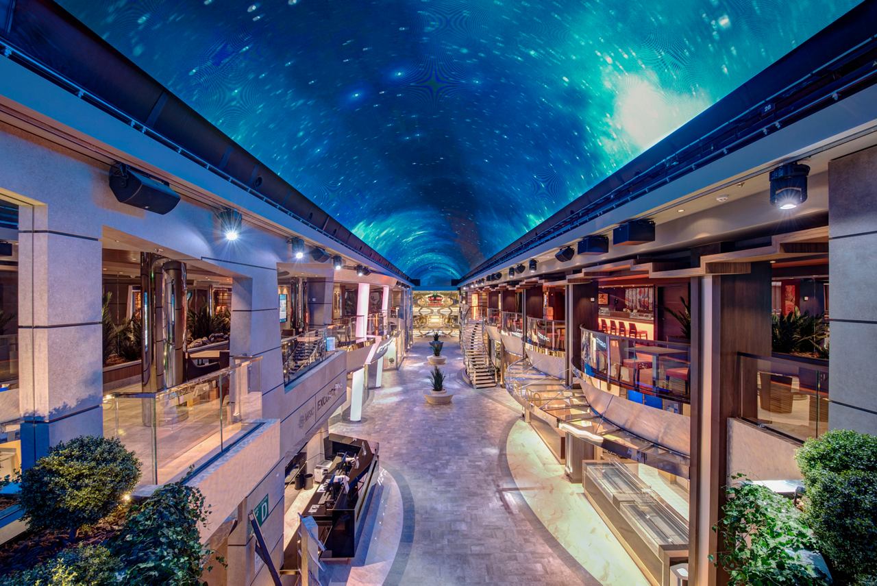 A vibrant promenade on MSC Meraviglia, illuminated under a starry sky, inviting guests to explore and enjoy | MSC Cruises