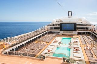 A panoramic view of the MSC Meraviglia's deck featuring a pool and large LED screen, with the sea in the background | MSC Cruises