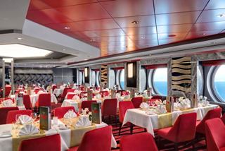 A vibrant dining area with elegantly set tables and chairs, featuring large windows for stunning sea views | MSC Cruises