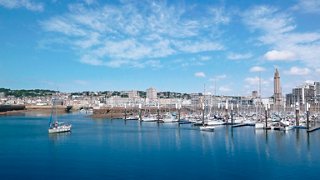 Une vue pittoresque du port du Havre avec des bateaux sur la mer et la tour de l'église Saint-Joseph en arrière-plan | MSC Croisières