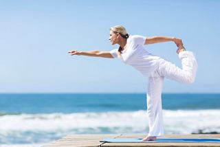 A senior woman practices yoga on the beach, embracing wellness and relaxation by the sea | MSC Cruises