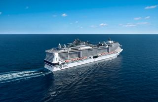 Aerial view of the MSC Meraviglia gracefully sailing across the serene sea under a clear blue sky | MSC Cruises