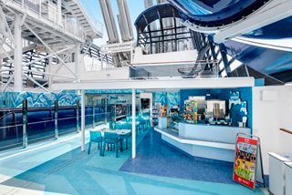 A vibrant bar area on MSC Meraviglia featuring a sleek counter, tables, and a water slide overhead | MSC Cruises